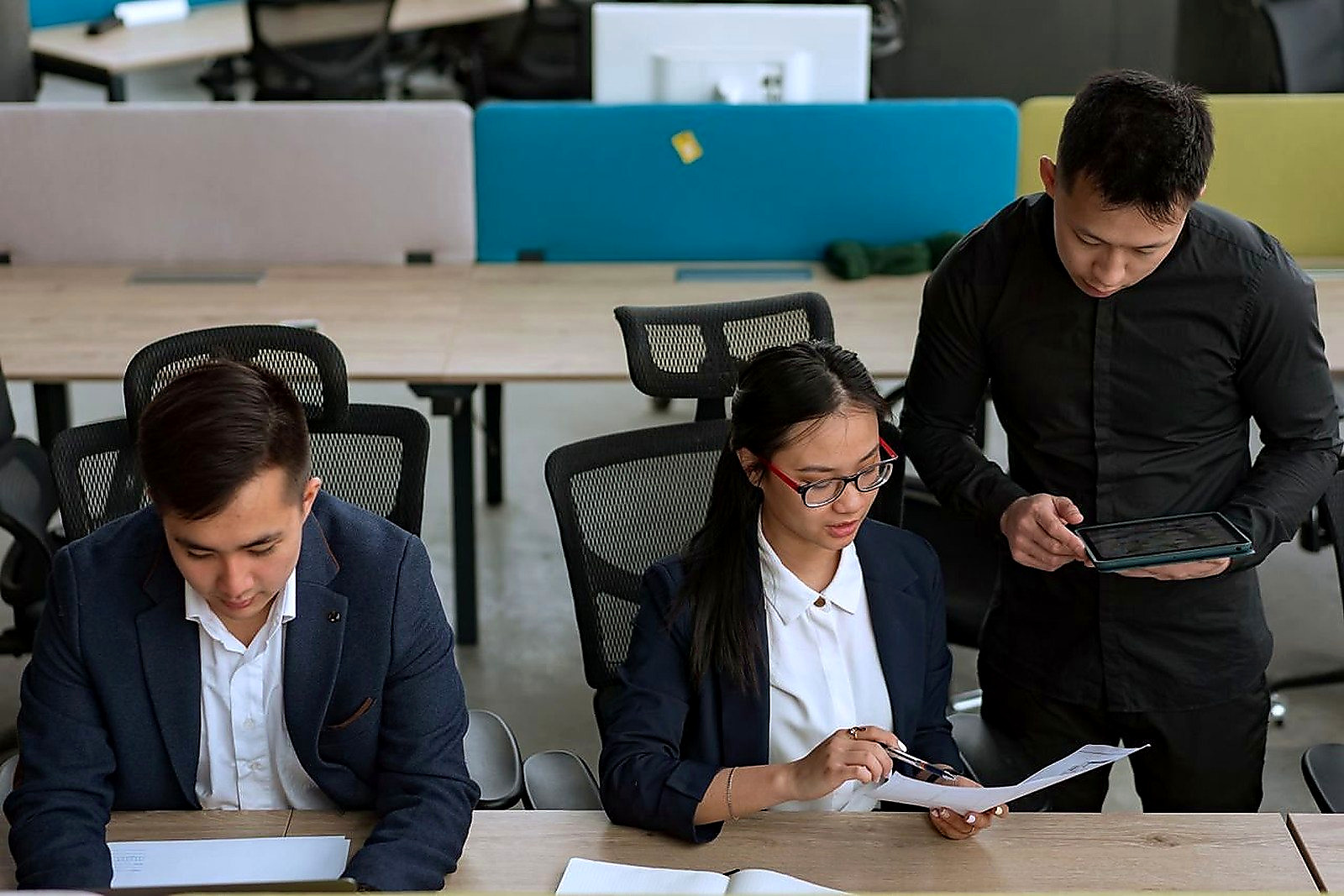 Free A professional team collaborating in a modern office setting, focusing on documents and technology. Stock Photo