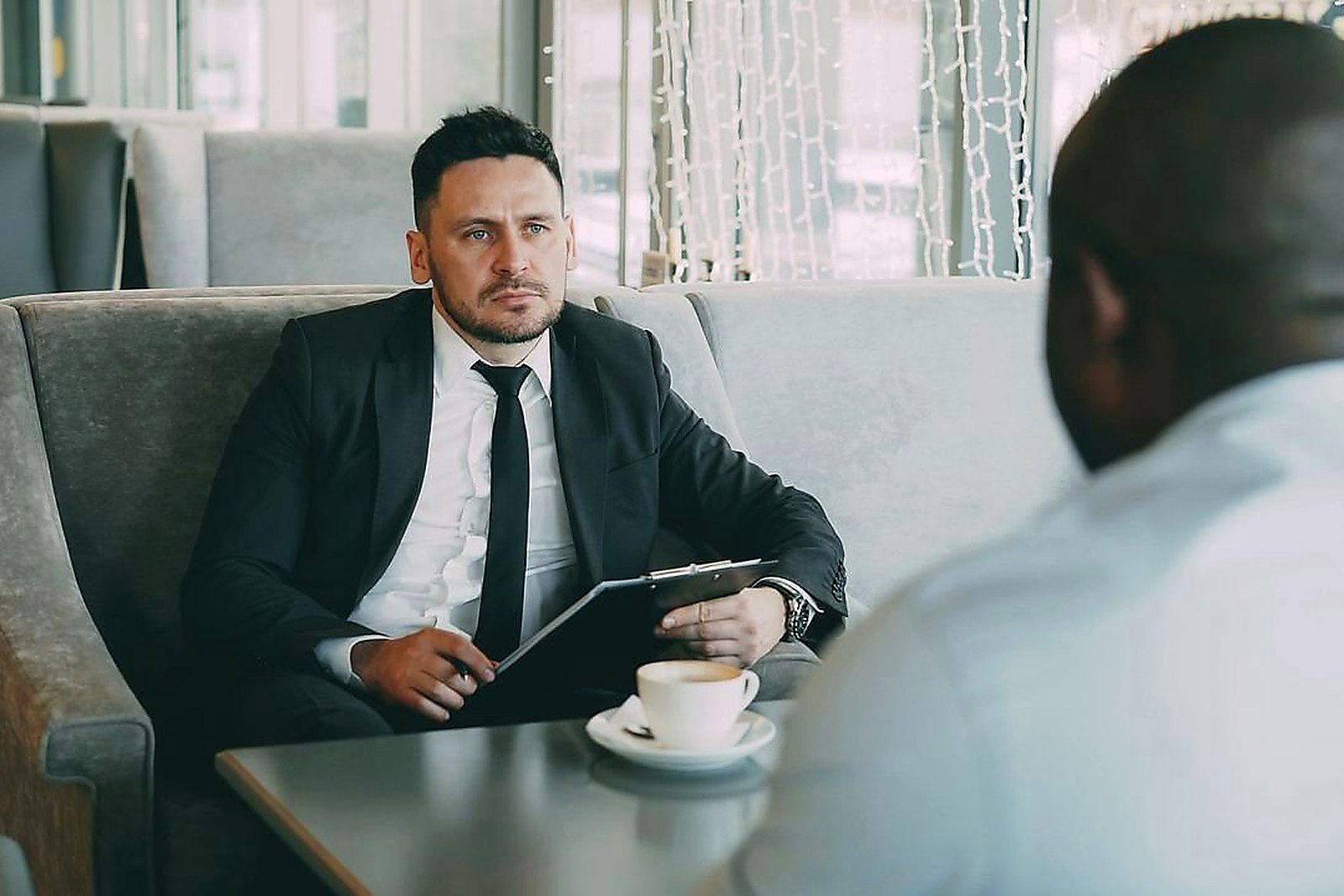 Free Two businessmen having a serious conversation over coffee in a stylish cafe setting. Stock Photo